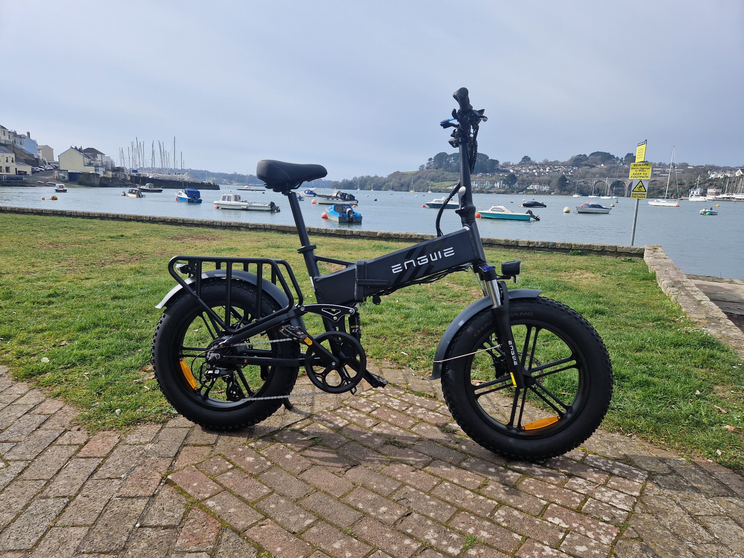 Engwe Engine |Pro 2.0 folding e-bike pictured on a green next to an estuary